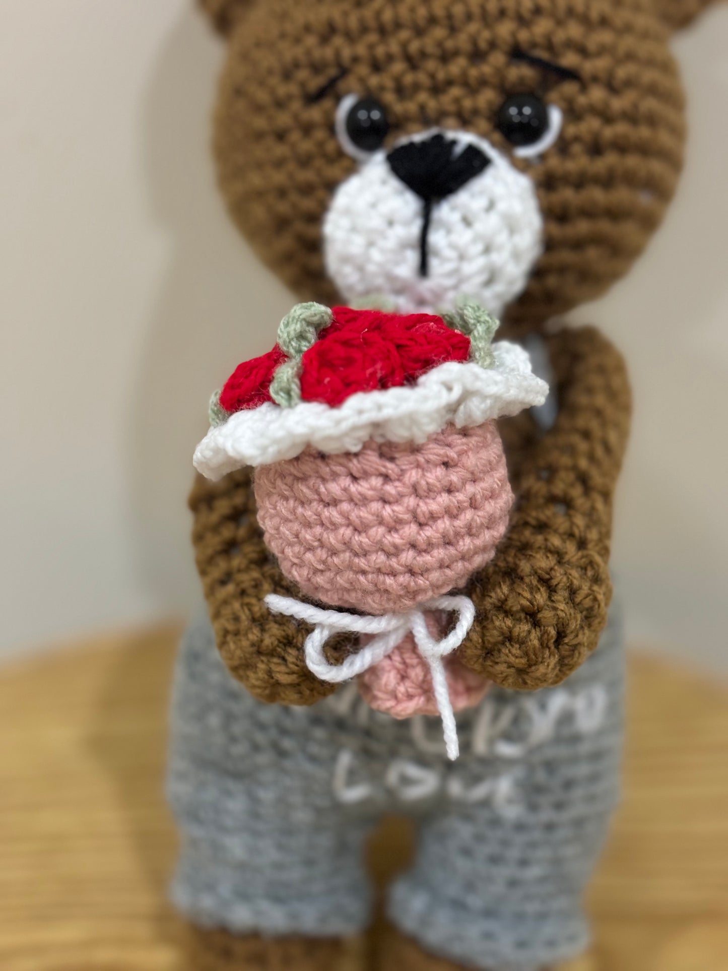 Crochet bear holding roses bouquet